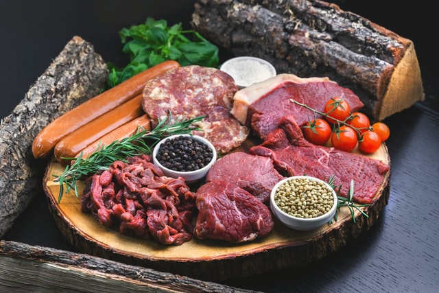 different kind of raw meat on platter with herbs